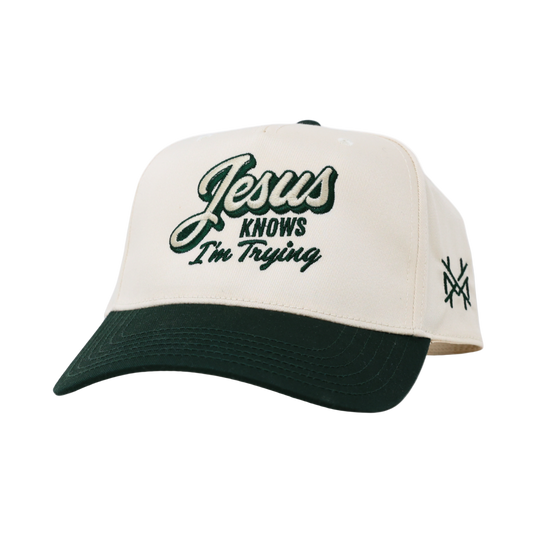 Cap with 'Jesus Knows I'm Trying' text on a white background
