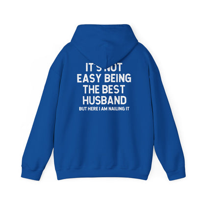 Best Husband Hoodie with white text on blue background reading 'IT'S NOT EASY BEING THE BEST HUSBAND BUT HERE I AM NAILING IT'.