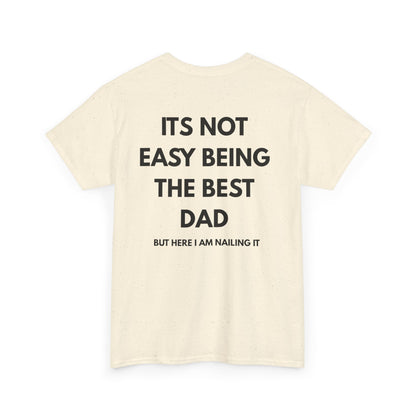 Not Easy Being The Best Dad But Here I Am Nailing It Shirt showing humorous text design on back of cream-colored t-shirt.