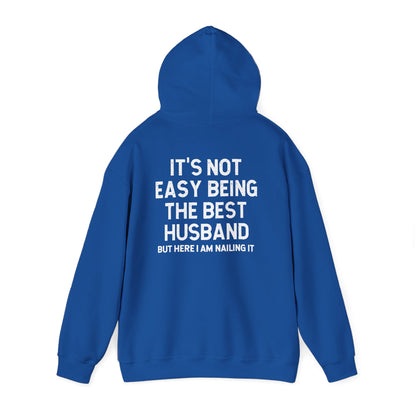 Best Husband Hoodie in blue featuring text on back that reads "It's Not Easy Being THE BEST HUSBAND But Here I Am Nailing It"