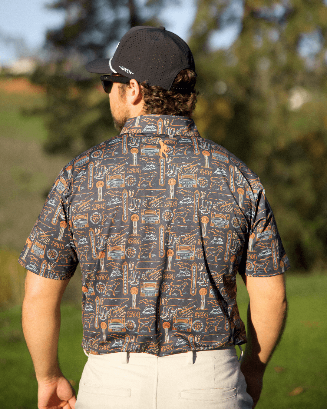 Back view of a man wearing the Tennessee football polo shirt by Haven Golf featuring Smokey Knoxville design.