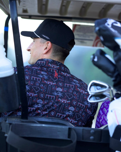 Man wearing South Carolina football polo shirt by Haven Golf in a golf cart, displaying Palmetto State designs, viewed from the back.