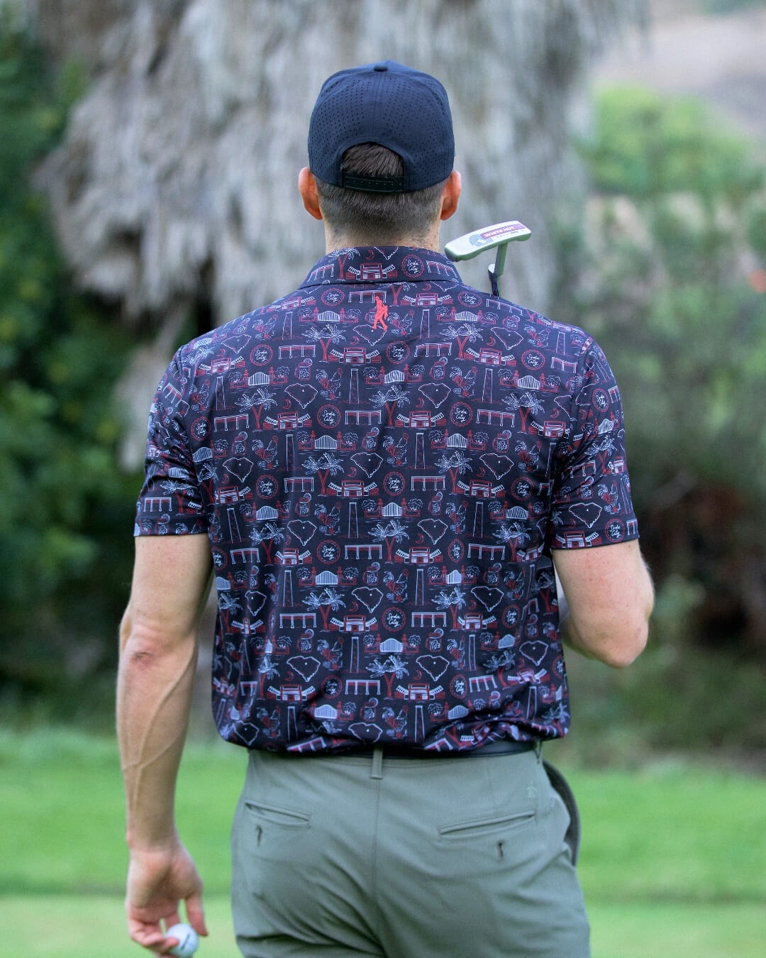 Man wearing South Carolina football polo shirt by Haven Golf with Palmetto design, standing on a golf course.