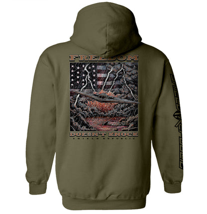 Freedom Doesn’t Knock Shirt with dramatic graphic and American flag elements on olive green hoodie.