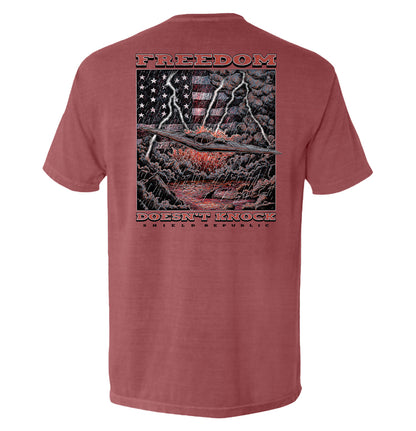 Freedom Doesn’t Knock Shirt with dramatic graphic of lightning and American flag on a stormy background, showcasing strength and independence.