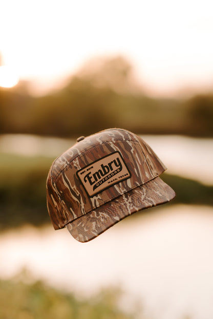 Brown Ranch Camo Trucker Hat with camo design floating outdoors, ideal for outdoor activities and everyday wear.