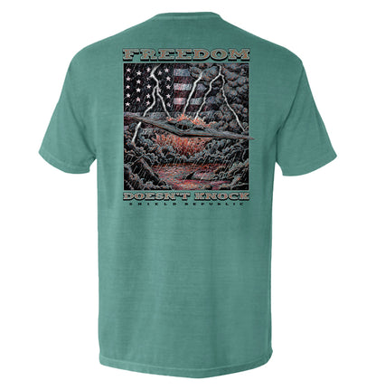 Freedom Doesn’t Knock Shirt with stormy sky and patriotic elements graphic on back, expressing strength and independence.