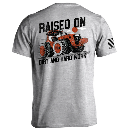Gray t-shirt with graphic of a tractor and text 'Raised on Dirt and Hard Work' on a white background