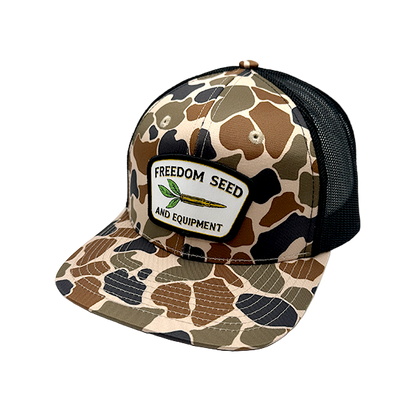 Camouflage-patterned cap with 'Freedom Seed' logo on a white background