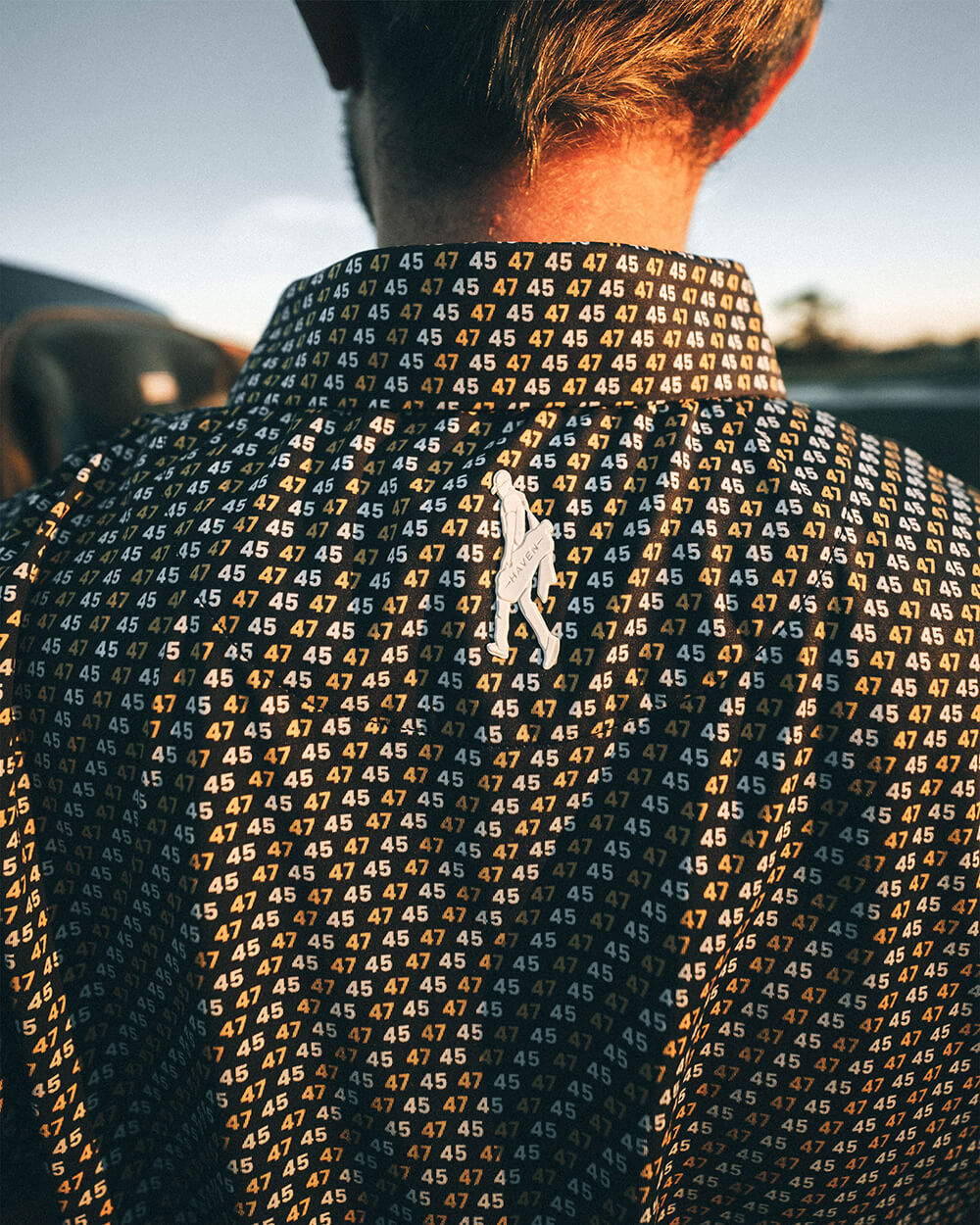 Back view of 45 47 polo shirt by Haven Golf, showcasing bold black-and-gold print with iconic numbers for subtle political style.